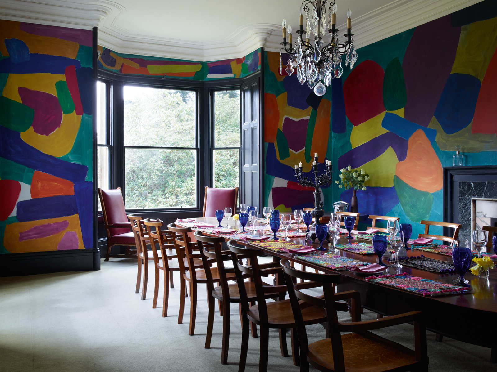 Мурал на стенах столовой кисти шотландского художника Фреда Поллока. Стол сервирован разномастной посудой и...